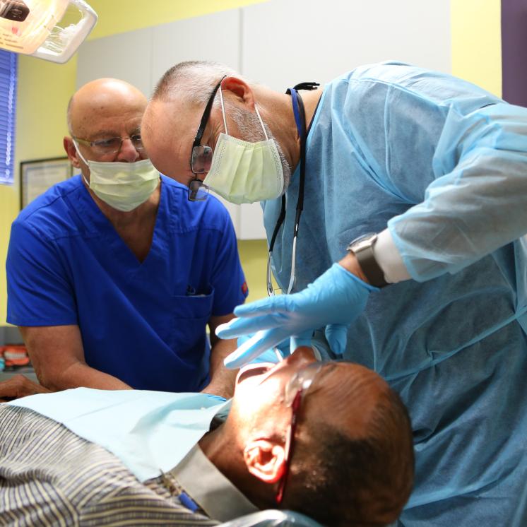 Two dentists examine a guest at SVdP's dental clinic.