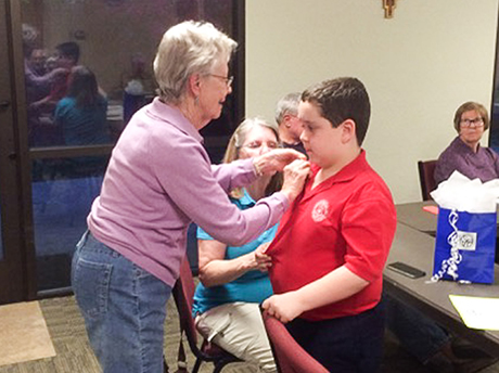 Adrien is pinned with an antique gold SVdP pin during a conference meeting.