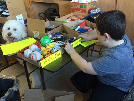 Adrien prices his toys to sell at a garage sale to benefit SVdP.