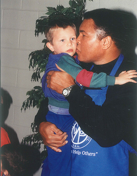 Boxing legend Muhammad Ali holds a child in SVdP's dining room.