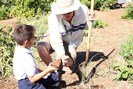 David Smith teaches Sebastian from the Dream Center about healthy soil.