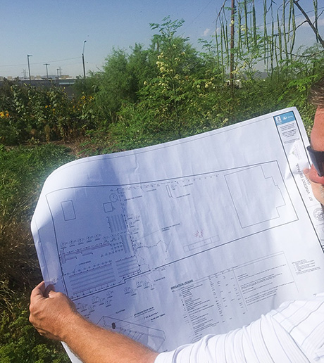 Creative Environments employee looks at irrigation system plans for SVdP's Urban Farm.