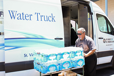 Joseph loads the water truck with water bottles