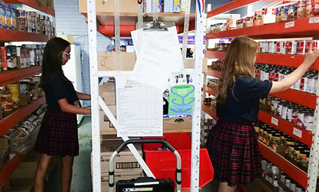 Jacey and Cienna pack food boxes at Our Lady of Mount Carmel food pantry.