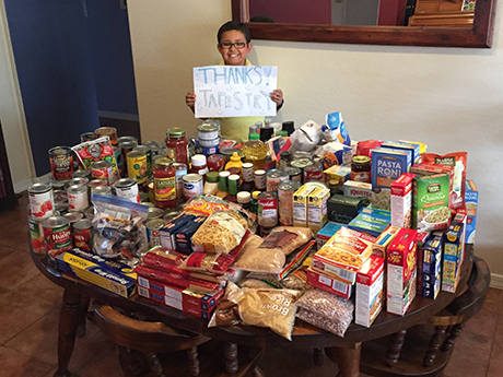 Kegan displays all the food his neighbors donated during his food drive.