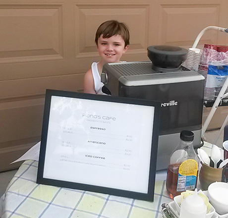 Max sits behind his coffee shop stand.