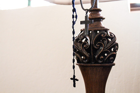 Rosary cross necklaces hang on a lamp in Richard's home.