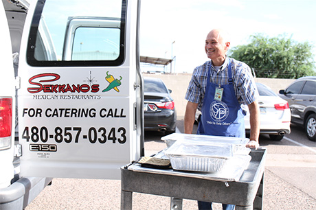 Ernie Serrano (Jr.) unloads food to serve during St. Vincent de Paul's lunch service in Mesa.