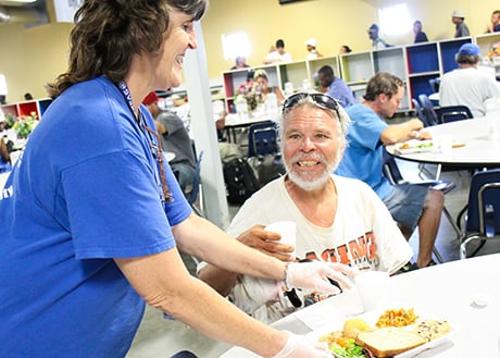 Theresa brings a guest his meal during lunch in SVdP's downtown Phoenix dining room.