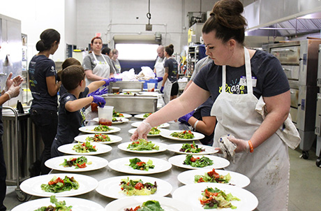 Wildflower Bread Co. staff member prepares salads during the Kitchen Takeover.