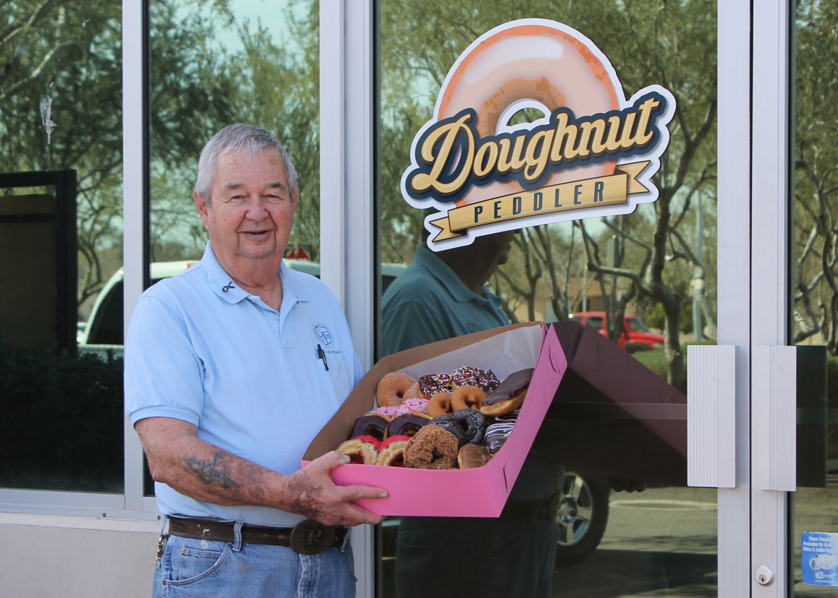 Vincentian volunteer Joe Rinker poses outside Doughnut Peddler with a variety box of doughnuts.