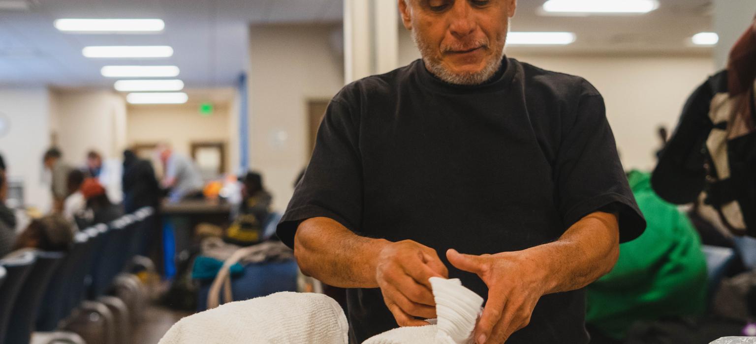 Exiting Homelessness header Man folding towels on a counter