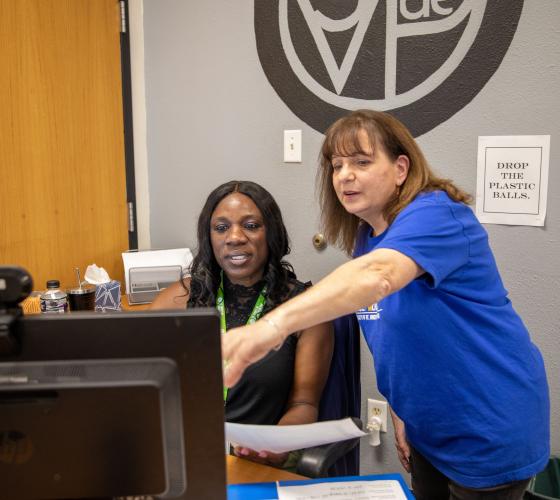 Two women pointing at a computer screen