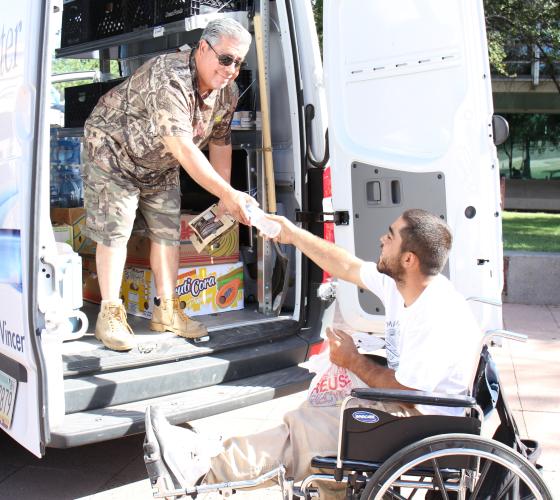 Street Outreach VSO Header Older man in the back of a van handing a water bottle to man in a wheelchair