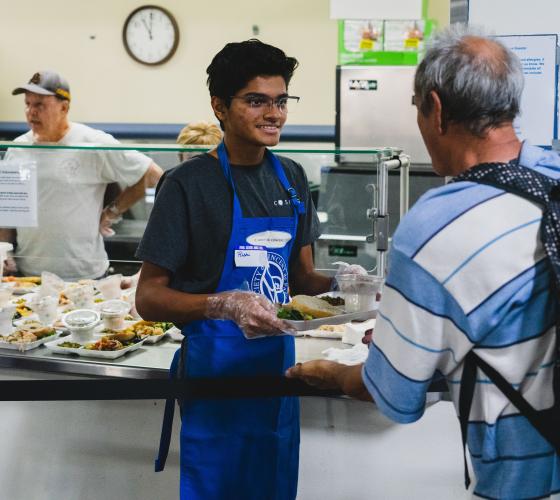 Young man handing a tray of food to an older man