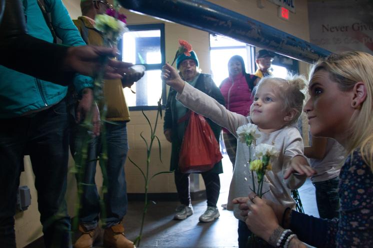 Little girl volunteering hands a flower to a guest of SVdP's Phoenix Dining Room