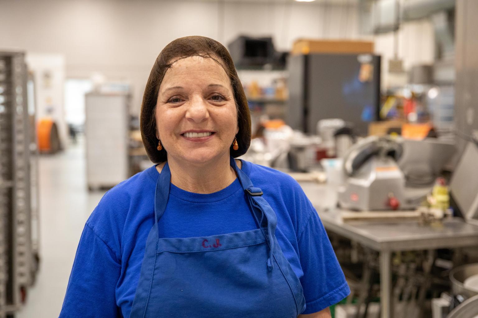 Woman in apron and hairnet looking into the camera