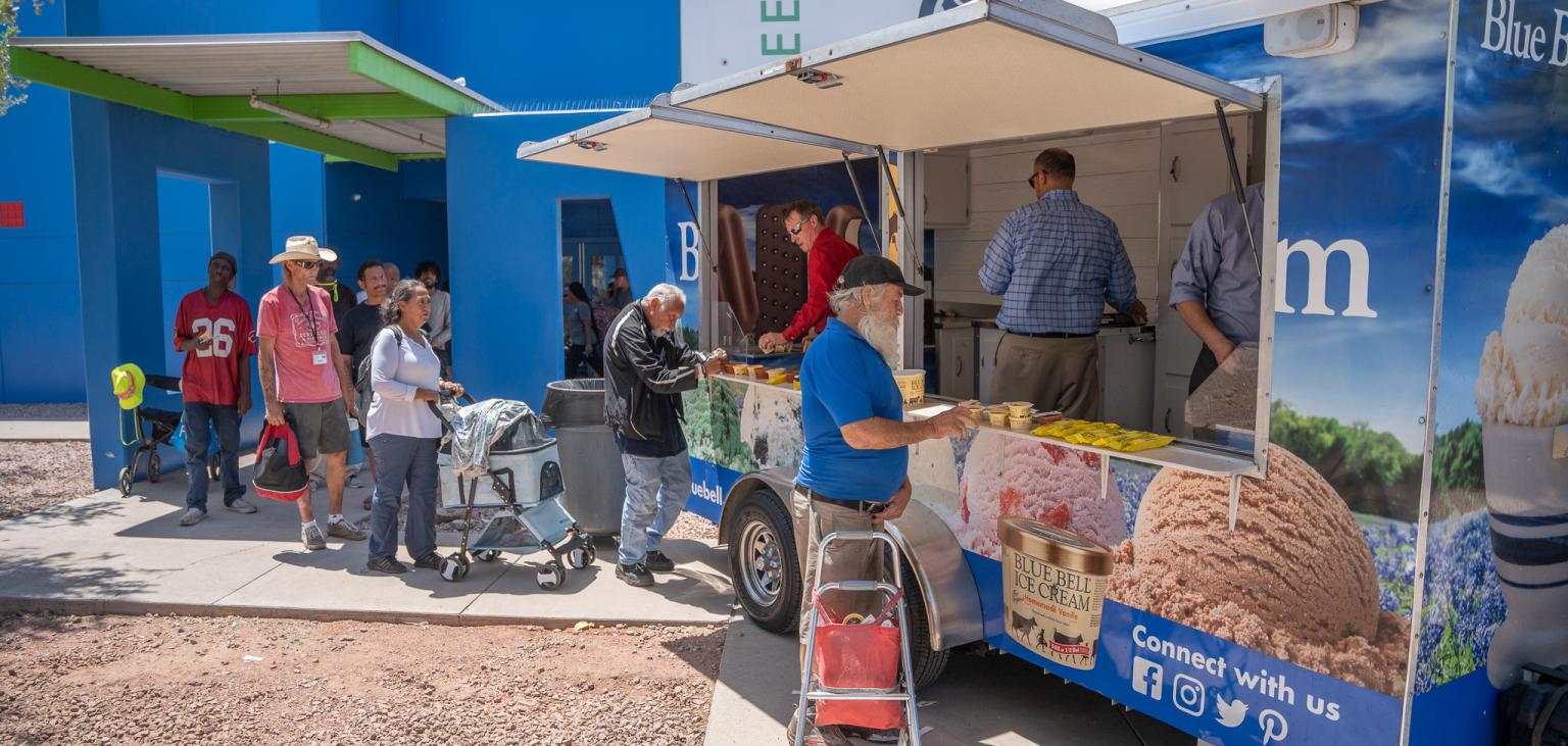 A line of guests at SVdP's Phoenix Dining Room await their turn to get ice cream from the Blue Bell Ice Cream refrigerated trailer.