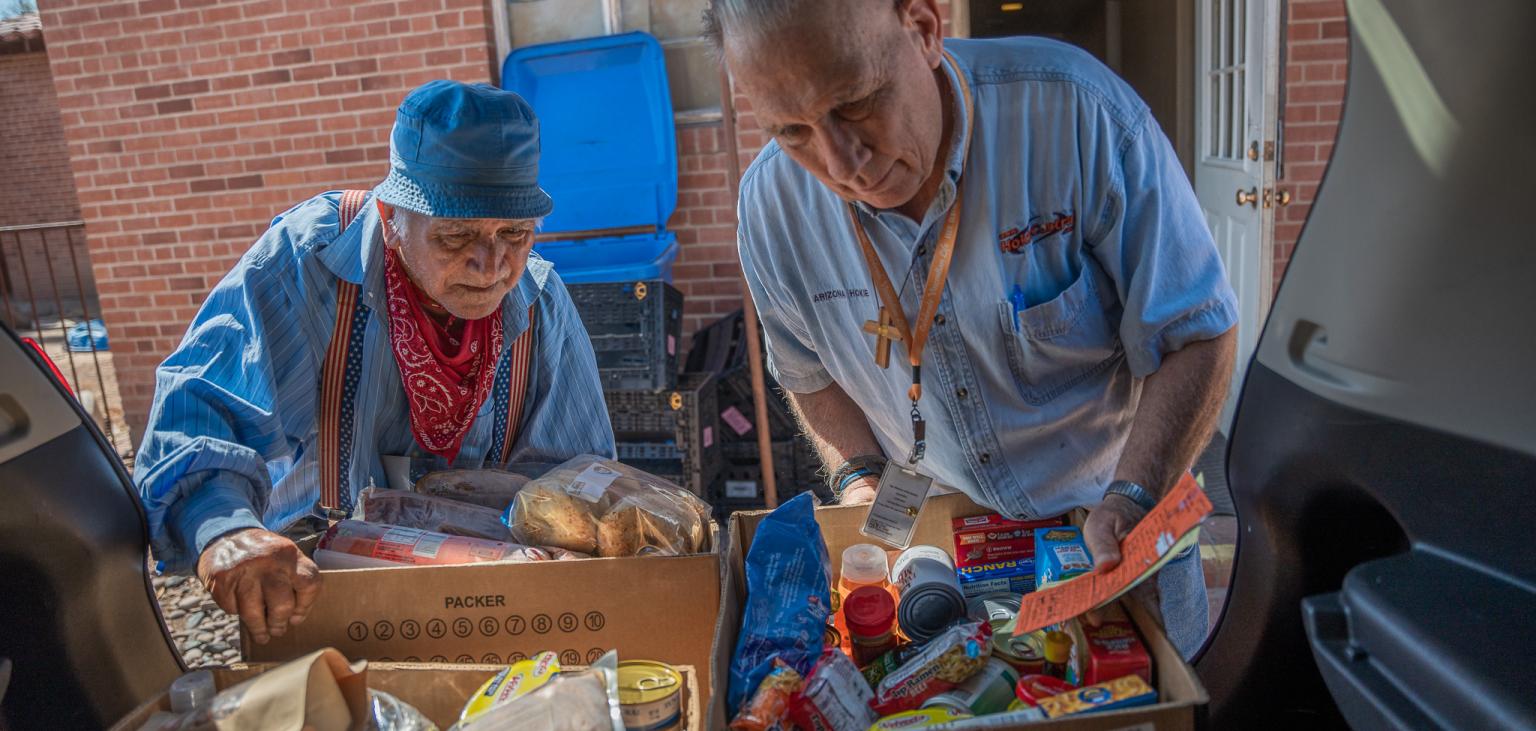 Two Vincentian volunteers load groceries in the back of a car to be delivered to families in need in their community.