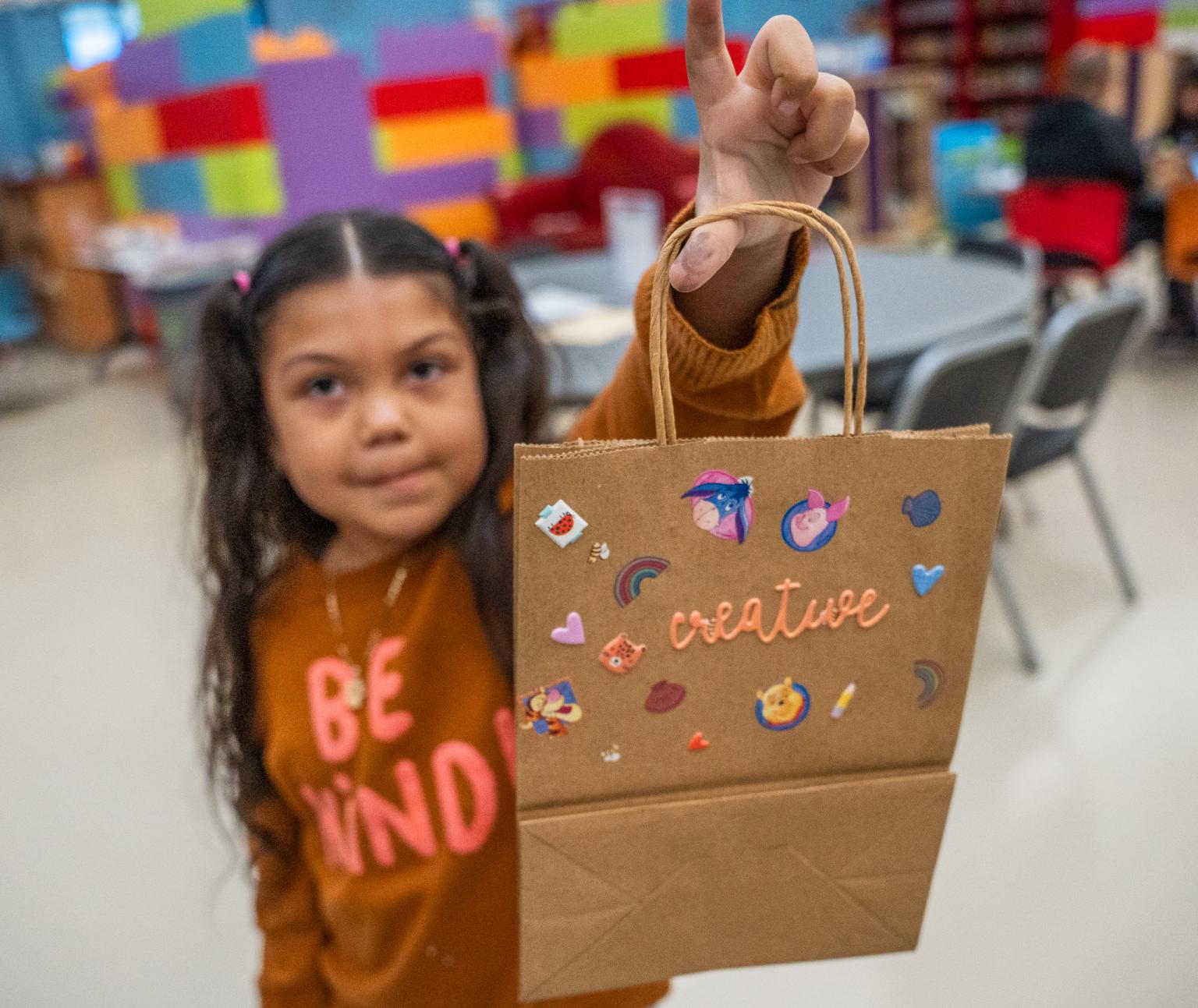 A young guest at FEM holds up her handmade Valentine's Day bag.