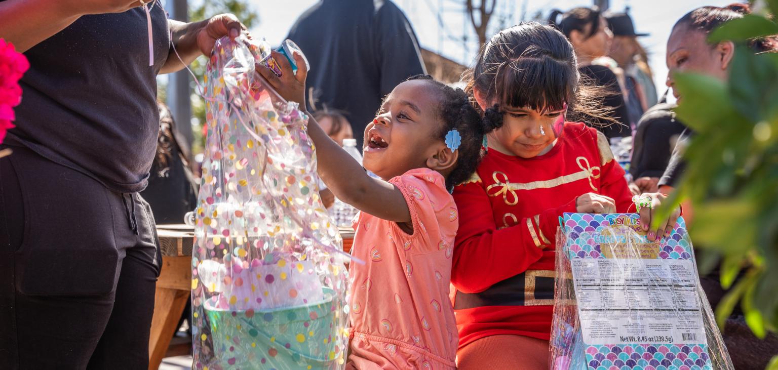 A girl grins at a toy she received in an Easter Basket from SVdP.