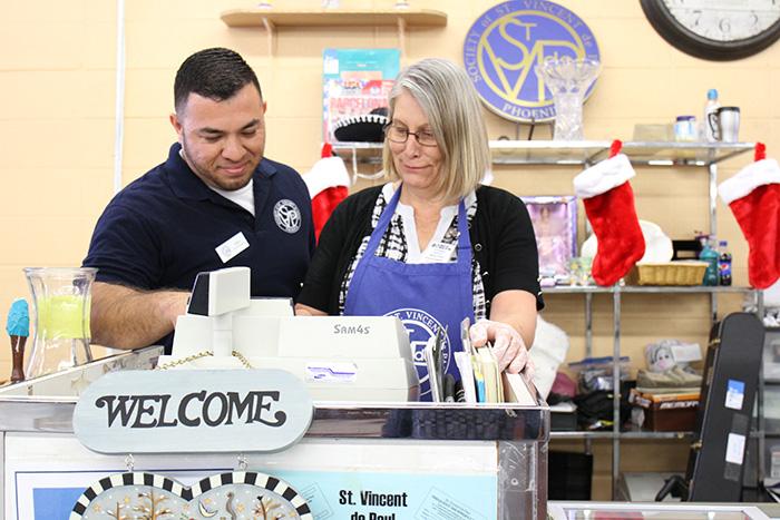Mesa Thrift Store manager Alex Loya trains Encore Fellow Josie on cashier duties.