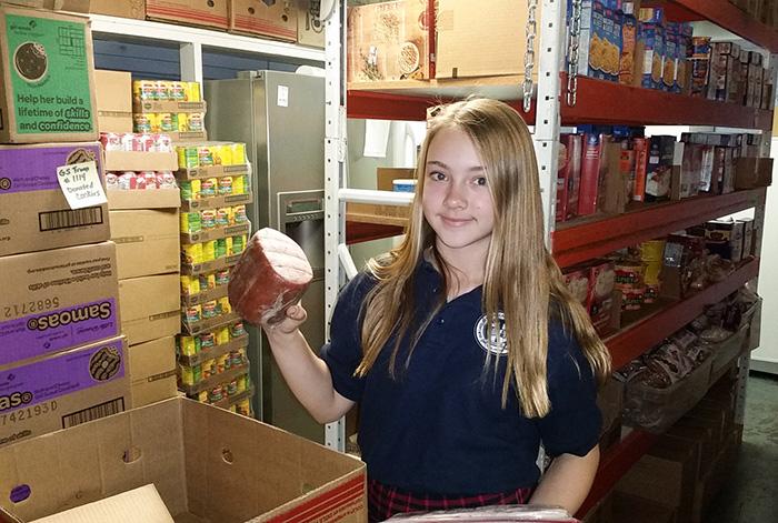 Jacey packs a food box at Our Lady of Mount Carmel food pantry.