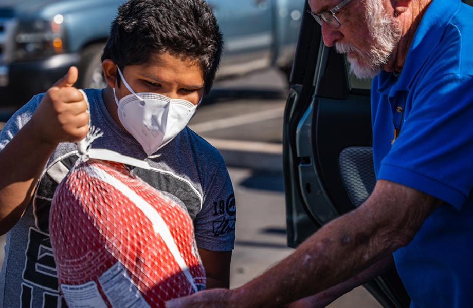 A Vincentian hands a turkey to the boy of a family in need this Thanksgiving