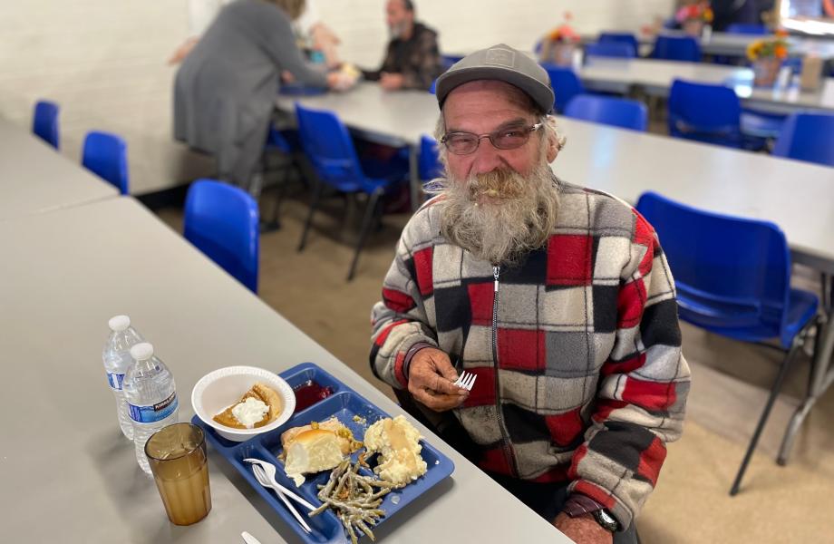 Man eating a thanksgiving meal in the dining room looking up at the camera