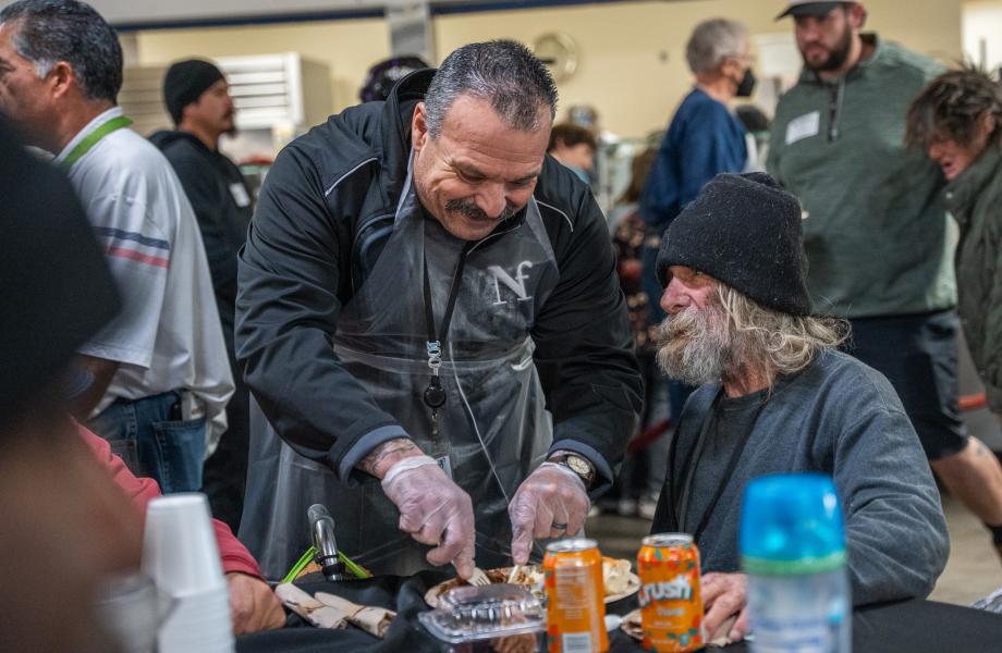 A volunteer cuts a steak for a guest at SVdP's Phoenix Dining Room.