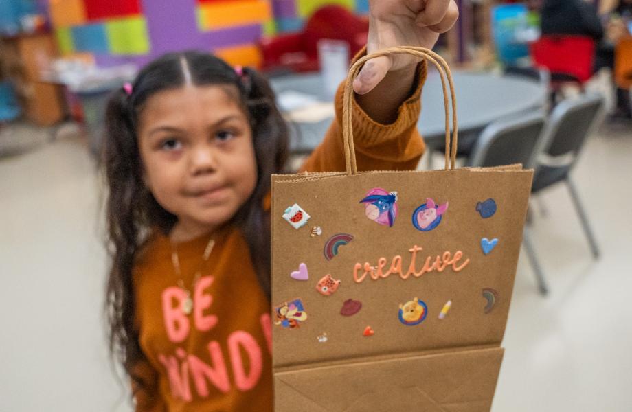 A young guest at FEM holds up her handmade Valentine's Day bag.