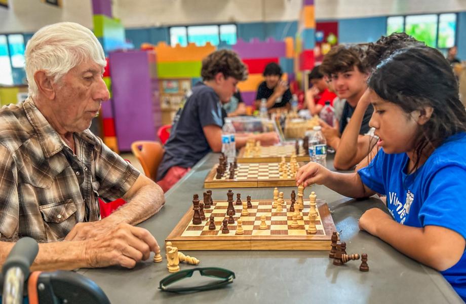 Older Ozanam Manor resident Tobias plays chess with the young Dream Center student Victoria.