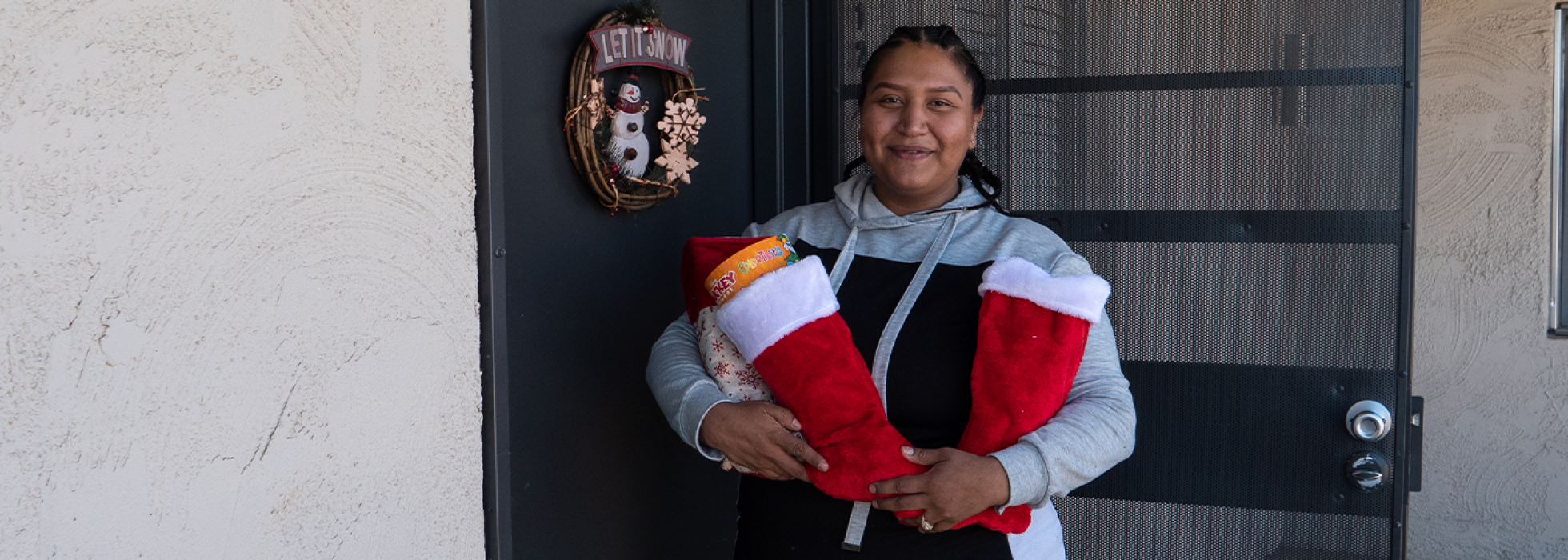 Woman standing in front of her apartment holding two stuffed stockings