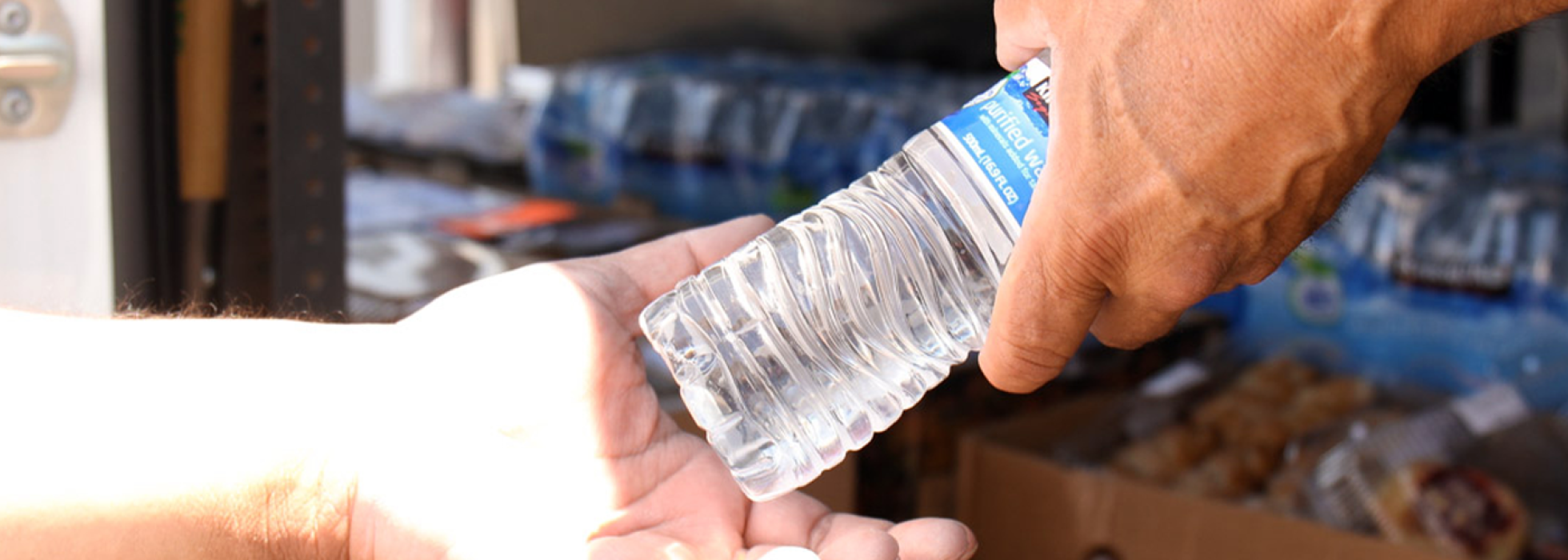 person handing a bottle of water to another person