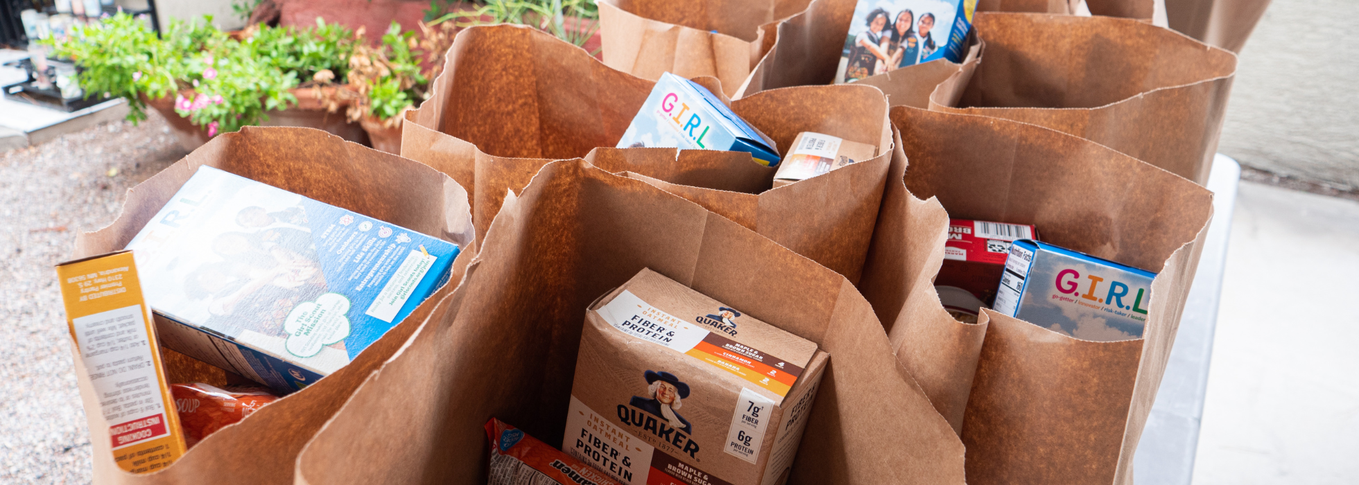 Brown paper bags stacked together and filled with food