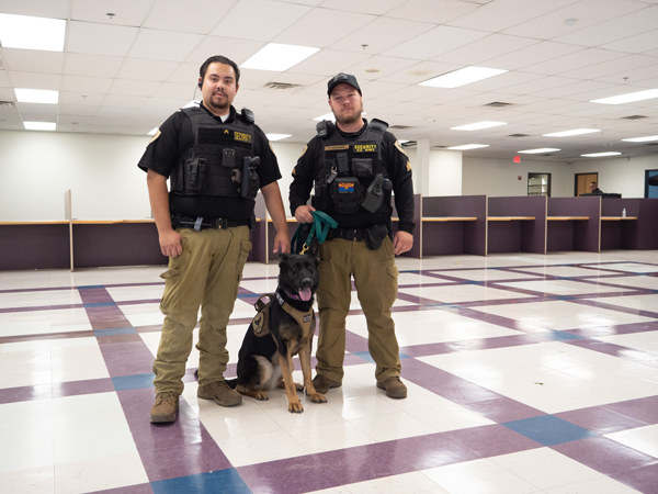 Two security officers posing with a dog