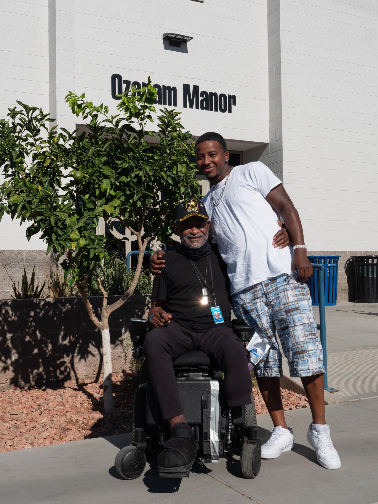 Man in a wheelchair and his son posing in front of building