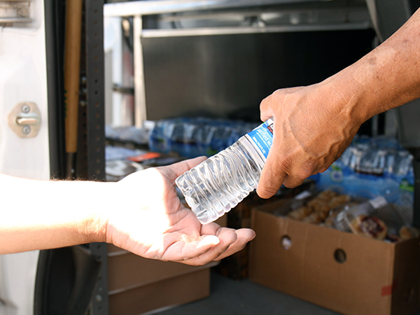 One person handing another person a bottle of water