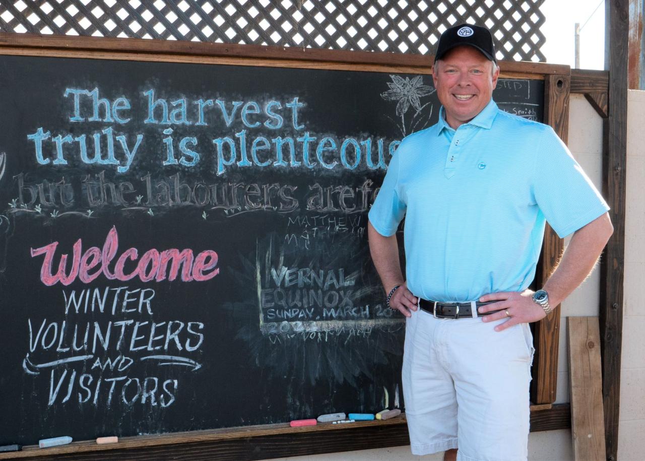Man posing in front of a chalkboard at the SVdP Urban Farm