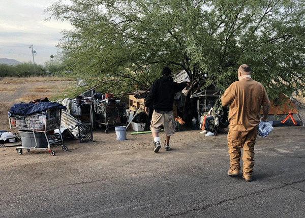 Two men walking over to a homeless encampment