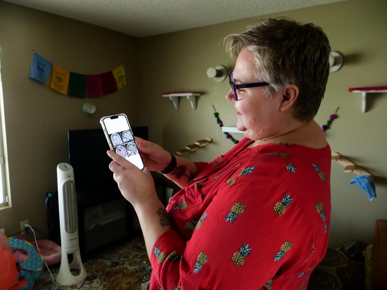 Woman standing in her living room showing a picture of her phone