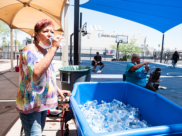 woman standing by a tub of ice drinking water