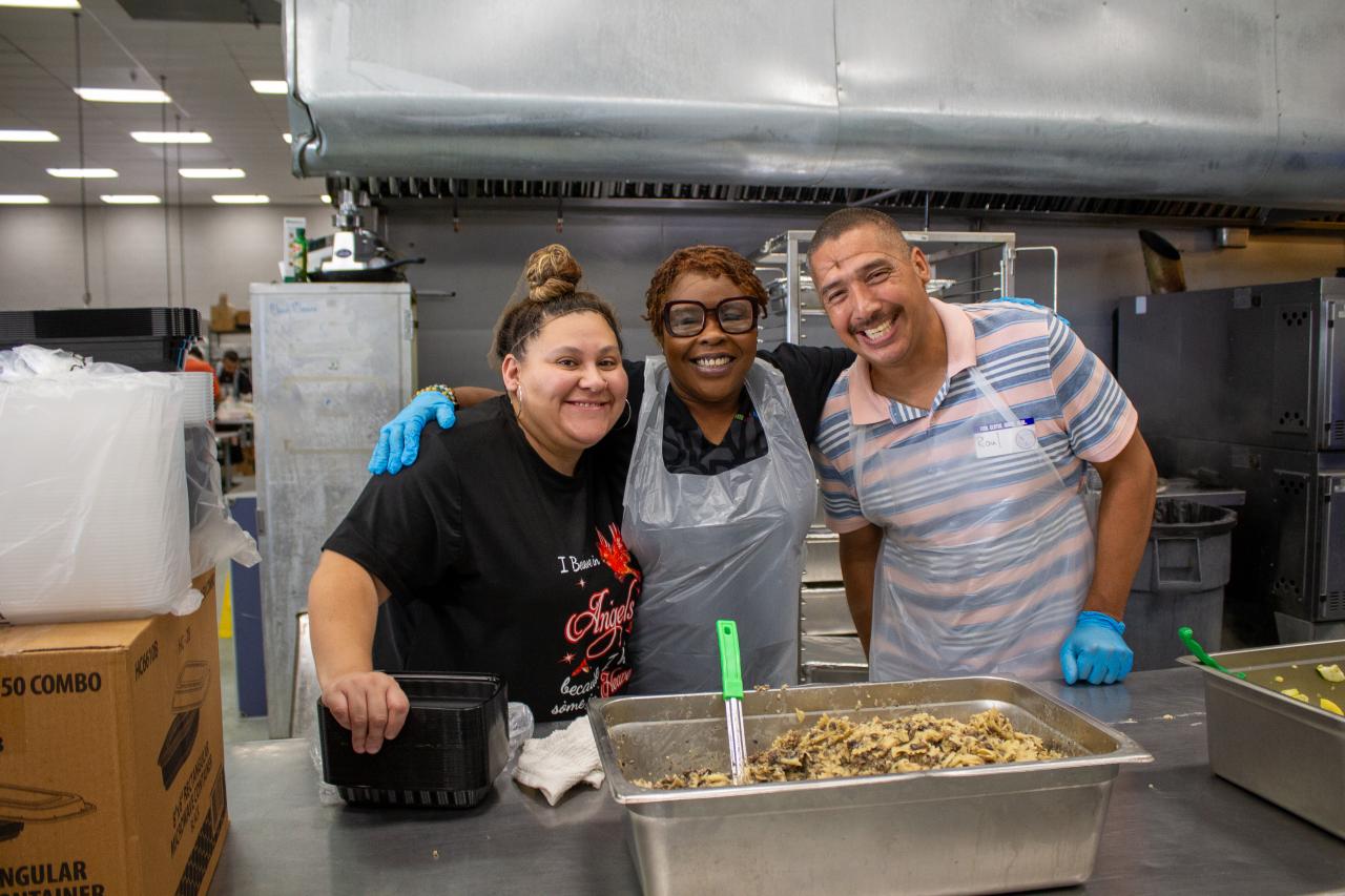 Donna Williams poses with SVdP cook and volunteer coordinator Dominique Montoya (at left) and another kitchen volunteer 
