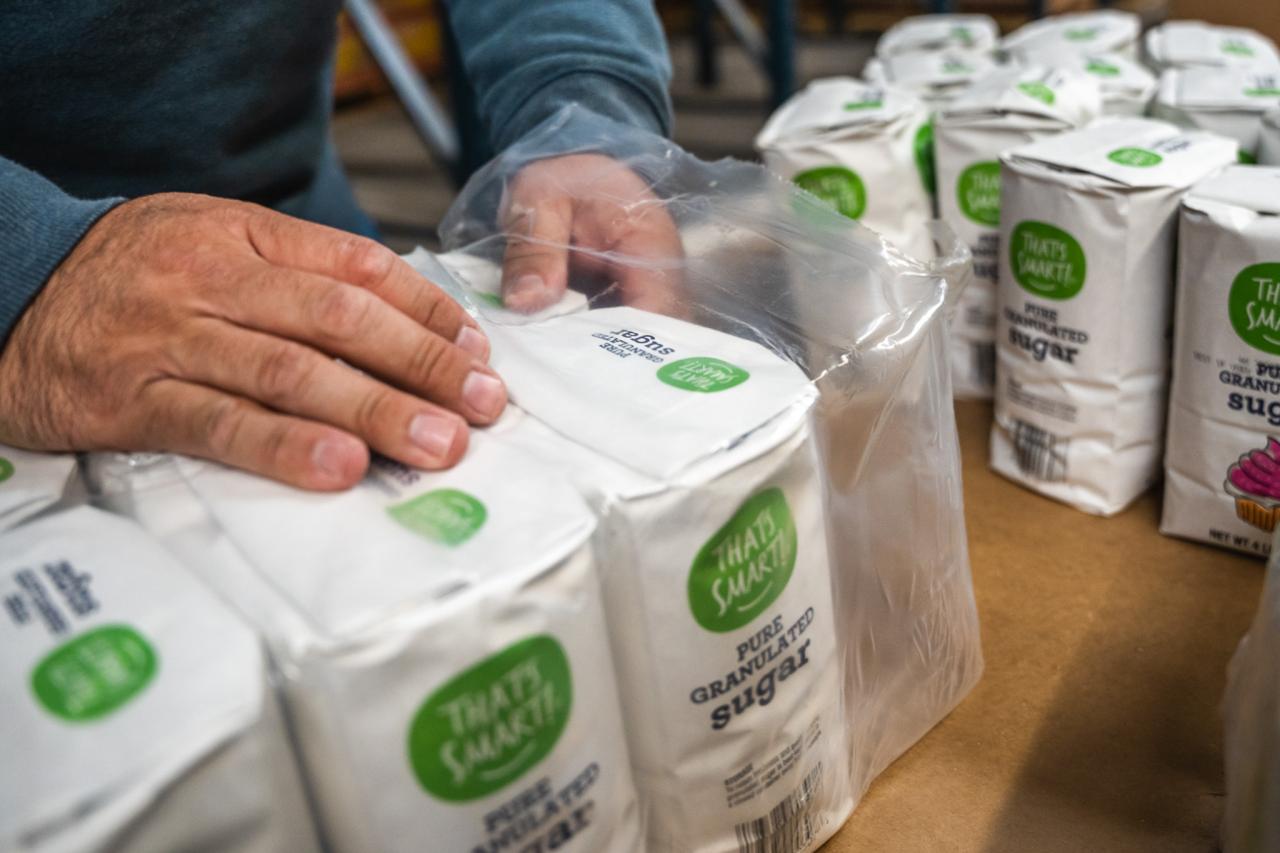 A volunteer takes out bags of sugar.