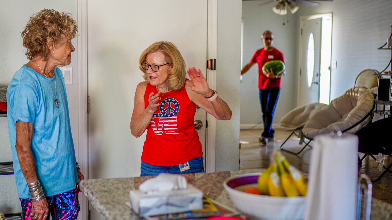 Paula talks with a Vincentian as another brings food into her home.
