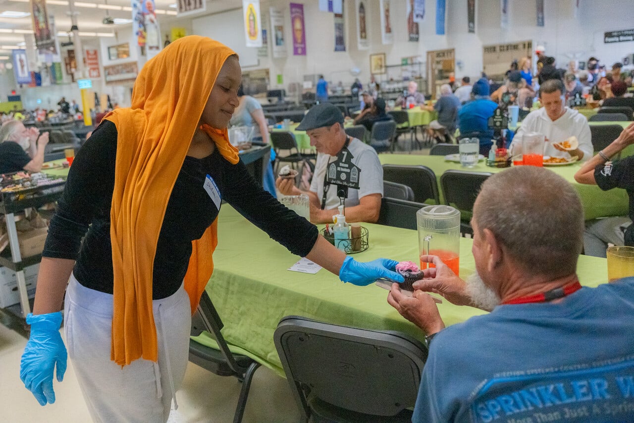 Shifaa hands out dessert to a guest at SVdP's FEM.
