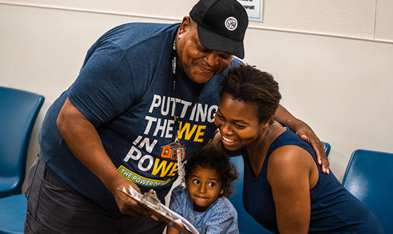 Man putting his arm around a woman and child in the resource center